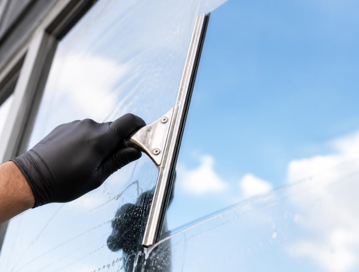Professional squeegee gliding across a spotless glass pane